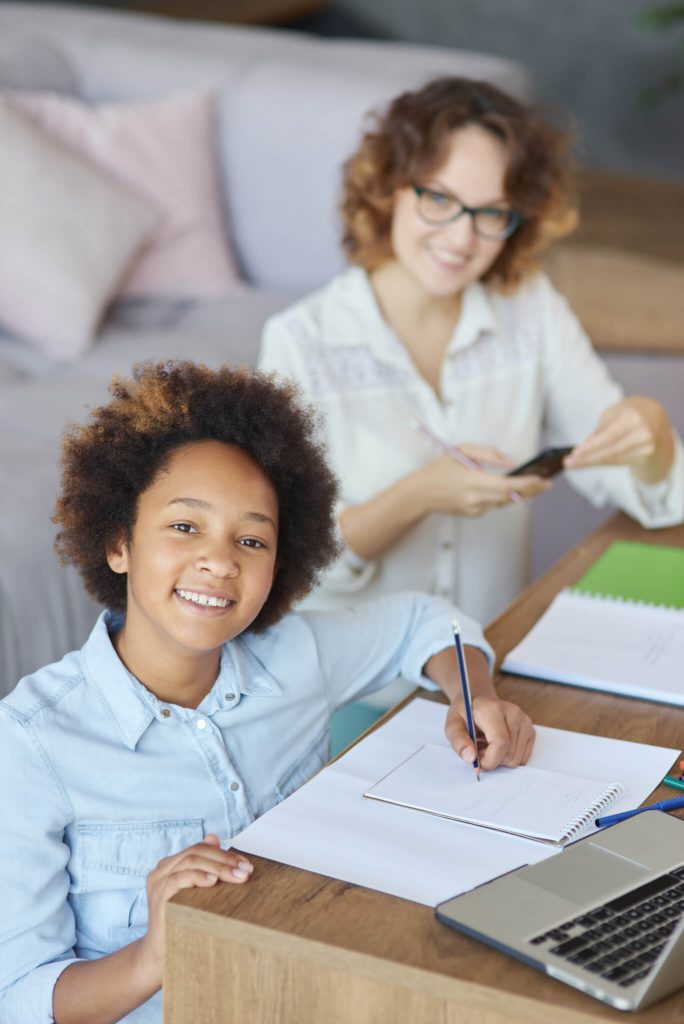 radiate happiness happy mixed race teen schoolgirl smiling at camera while having a lesson with